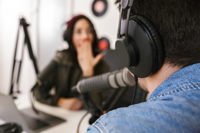 Man and woman in white shirts podcasters interview each other for radio podcast