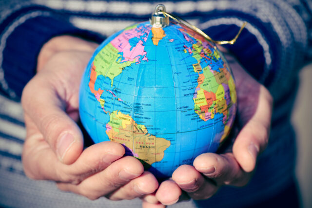 young man with a world globe as a Christmas ball in his hands