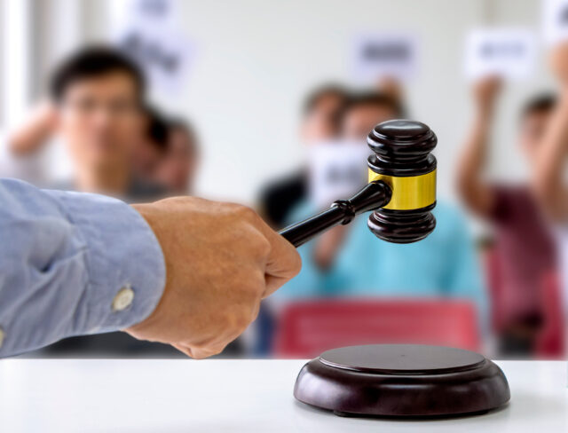 The person carrying the auction holds a wooden hammer in his hand to make a bid to sell the product.